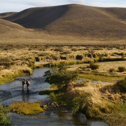 Two anglers standing in stream within an Argentinian landscape.